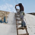 الخطوة الأولى تتمثل بطلاء الشعارات والكتابات بطبقة من الدهان تمهيدا للرسم على الجدار.
